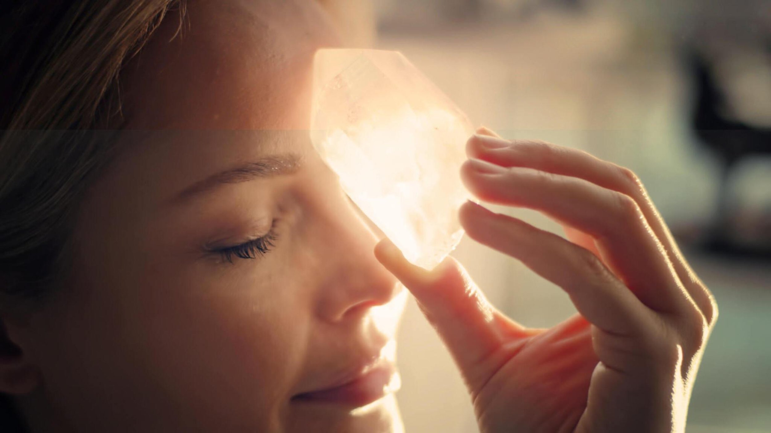 past life regression hypnosis woman holds crystal to third eye