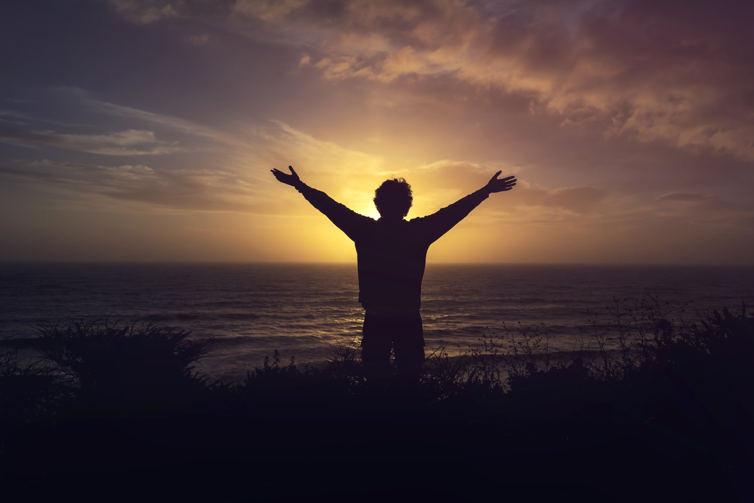 spiritual life coaching person with arms outstretched looking toward the sun