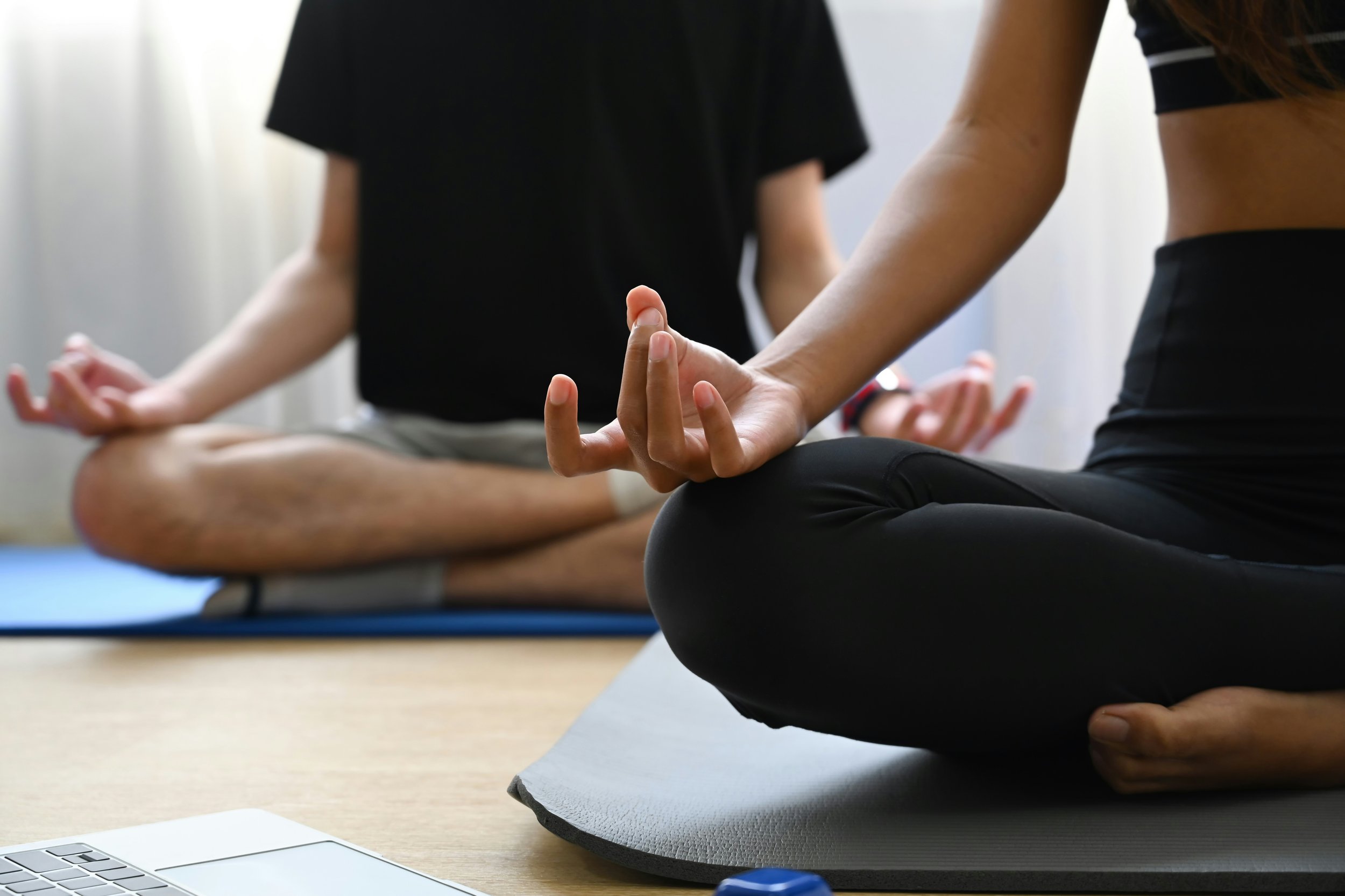 Two people in a relaxing yoga pose with Sedona's iconic red rock formations in the background, showcasing a peaceful yoga session.